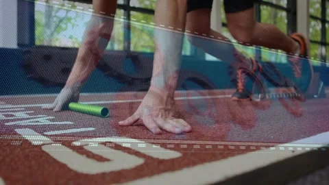 Runner kneeling at start placing green baton gripping track and adjusting blocks Stock Footage 329424637