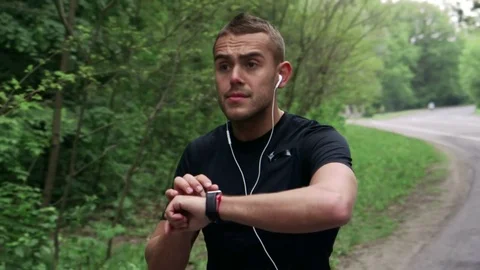 Runner looking at his smartwatch while running in the forest Stock Footage 75545697