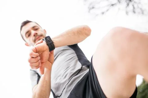 Runner looking at his watch from below Stock Photos