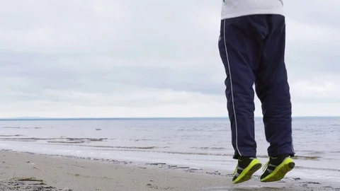 Runner man on beach is doing jumping exercise Stock Footage 82410949