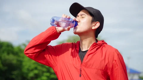 Runner man drinking water after jogging with running track background. Stock Footage 248123088