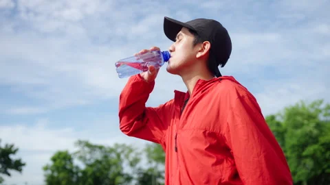 Runner man drinking water after jogging with running track background. Stock Footage 248123090