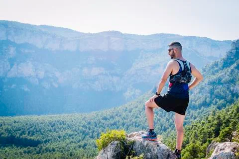 Runner man up on a mound of rocks looking at the mountains. Foto stock