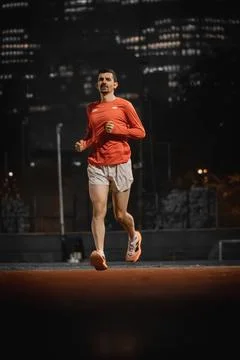 Runner mid stride with both feet off the ground at night Фото