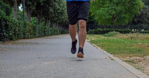 Runner mid stride on park path wearing black athletic shoes Stock Photos