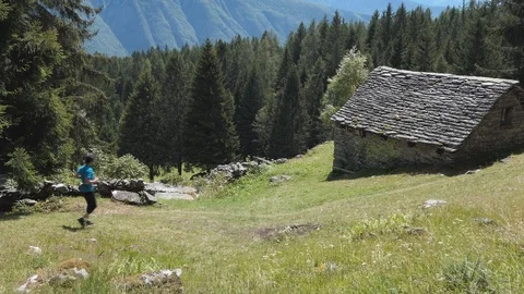 Runner on a mountain path and hut Video stock 114174822