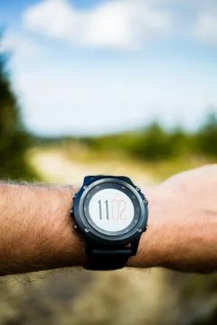 Runner on mountain trail looking at stopwatch, activity tracker Foto stock