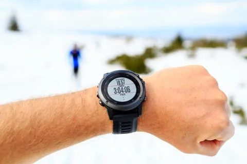 Runner on mountain winter trail looking at stopwatch, activity monitor Stock-Fotos