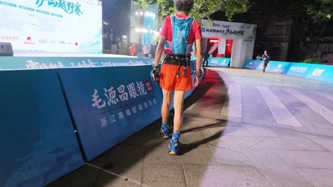 Runner in Orange Shorts Approaching Start Arch at Night, Lushan Trail Race Stock Footage 346701195