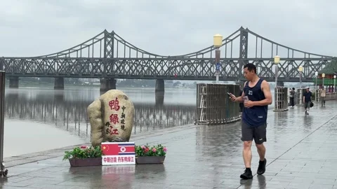 Runner Passes the China North Korea Friendship Bridge in Dandong Stock Footage 340176173