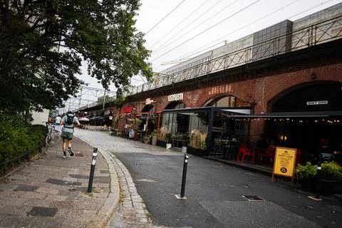 Runner passing outdoor cafes under historic brick railway arches along a co.. Stock Photos