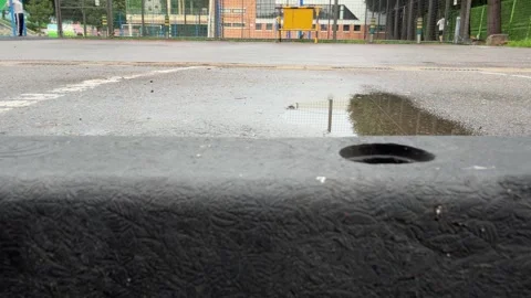 Runner Passing Rain Puddle on Wet Asphalt in Low-Angle Outdoor View Vídeo Stock 347290242