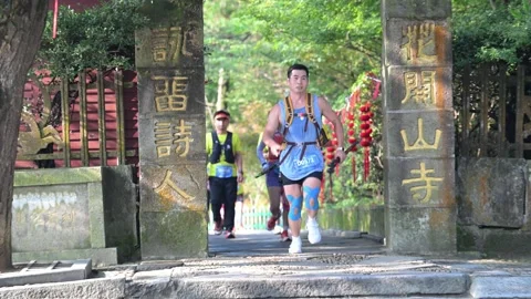Runner Passing Through Stone Temple Gate with Red Lanterns, Lushan Stock Footage 346718197