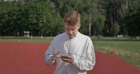 A runner pauses while jogging in a stadium to respond to a message. 库存影片 152971495