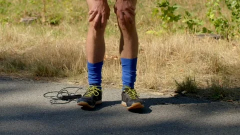 A Runner Pausing to Rest on the Path While Wearing Bright Blue Socks Stock Footage 318923251