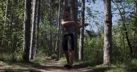 Runner performs warm-up routine in forest trail during sunny day in spring Stock Footage 346652088