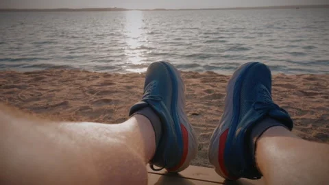 Runner resting on sandy beach after running along the river bank at sunset Video stock 292868856