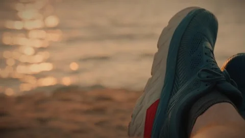 Runner resting on sandy beach after running along the river bank at sunset Video stock 292868905