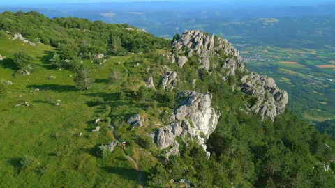 Runner on Rugged Mountain Trail with Lush Greenery and Rock Formations Vidéo 314202368