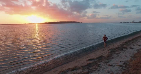 Runner running at seaside sunset reflections trackingshot aerial Stock-Footage 153519350