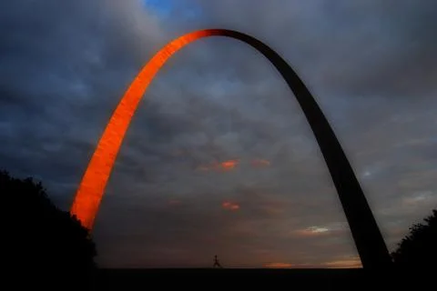 Runner running under the glowing St. Louis Arch at sunset Stock Photos