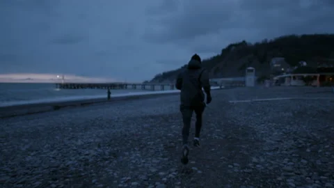 Runner runs away from a camera. Training on open air at nasty weather Stock Footage 147925495