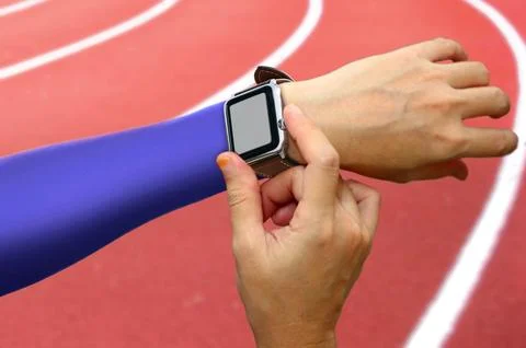 Runner setting her smart watch monitor before running on track in the stadium Stock Photos