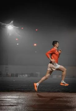 Runner in side view with misty floodlight and red lights behind 写真素材