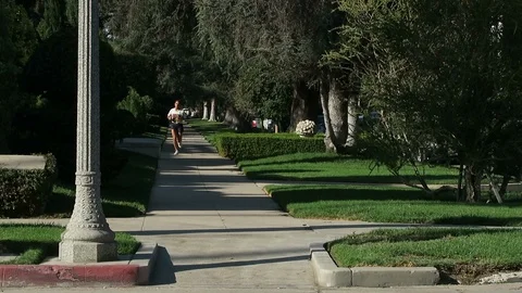 Runner on the sidewalk empty street￼ upscale neighborhood. Stock Footage 112768338