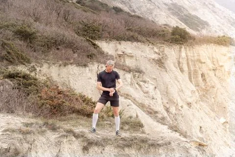 Runner standing on mountain, looking on watch Stock Photos