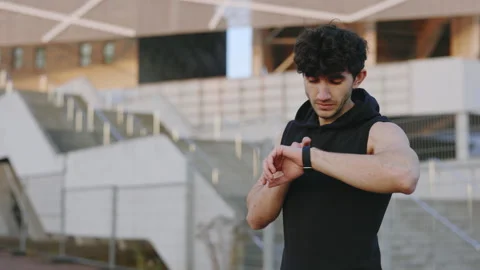 Runner Standing Outside, Looking at Smartwatch Fitness Bracelet. Fit Boy Athlete 库存影片 255296271