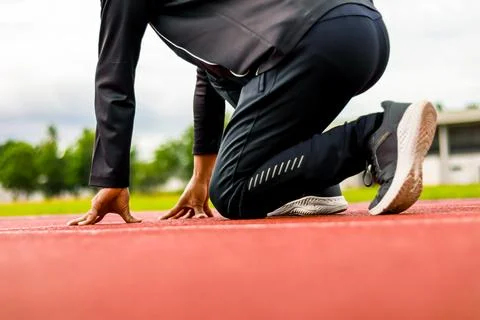 Runner in starting position on red track, ready for race, athletic focus Stock Photos