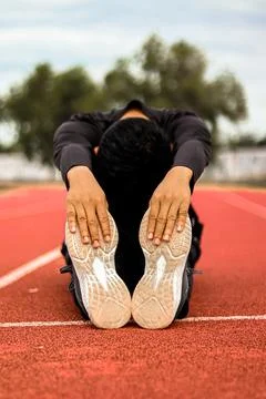 Runner stretching hamstrings on track, focus on feet and legs, active lifes.. Stock Photos