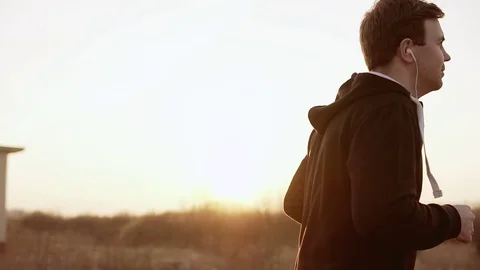 Runner at sunset outdoors in black hooded sweater. Slow motion Stock Footage