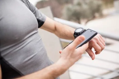 Runner synchronizing his watch and smart phone Stock Photos