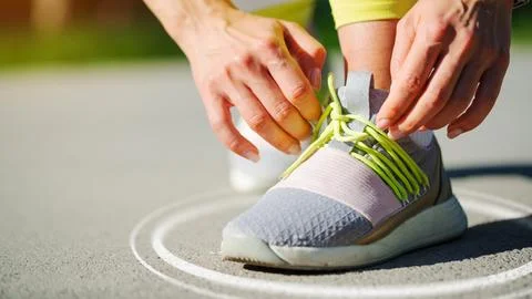 Runner ties shoelace on training ground before beginning workout session Stock Photos