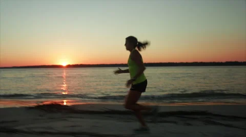 Runner is tracked as she runs by ocean at sunset Stock Footage 62926469