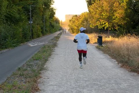 Runner training alone on a wide evening park trail Foto stock