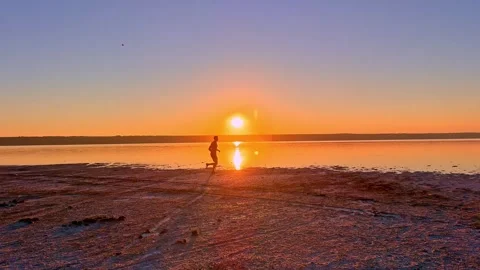 Runner Training Along Calm Estuary Shore at Golden Sunset Stock-Footage 344818139