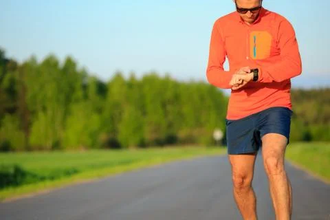 Runner training and checking stopwatch smart watch, cross country Foto stock