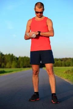 Runner training and checking stopwatch smart watch, cross country Stock Photos