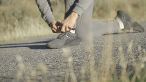 Runner tying shoes in a mountain road Stock Footage 163748839