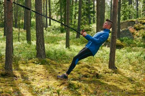 Runner using resistance band on tree in woods Stock Photos