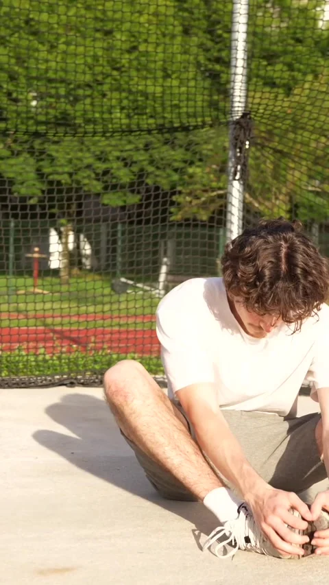 Runner warming up stretching knees and legs in a track Stock Footage 299896619