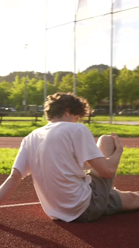 Runner warming up stretching knees and legs in a track Stock Footage 299896630