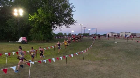 Runners competing in a high school cross country event at dusk, with Vídeo Stock 255651600