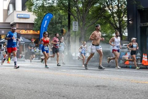 Runners jog through misting spray at Peachtree Road Race Stock Photos