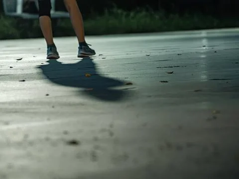 Runner's Legs Casting Long Shadow on Pavement During Night Exercise Stock Photos