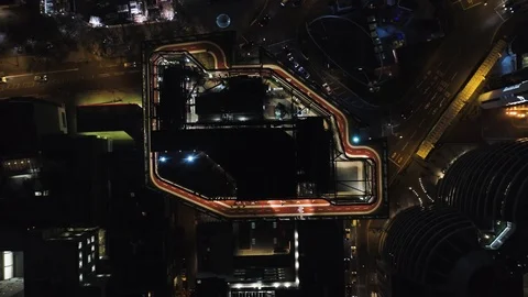 Runners on rooftop track at night with busy city life below, drone aerial 4K Stock Footage 101170552