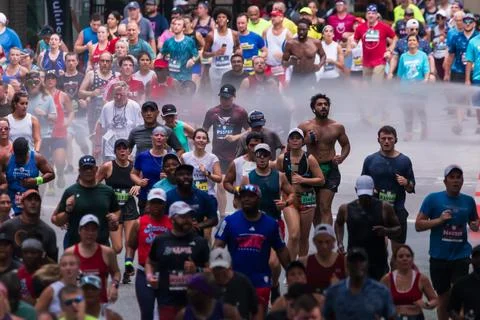 Runners run through misty spray at Atlanta Peachtree Road Race Foto stock